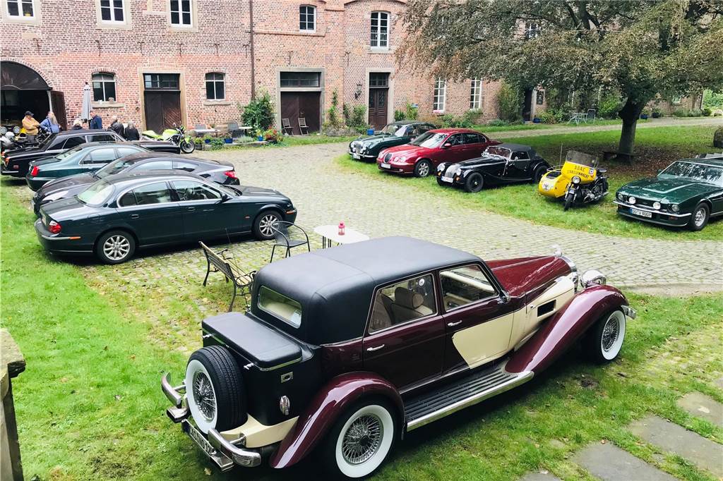 James Bonds Aston Martin und ein uraltes Motorrad im Schloss Bladenhorst Autos im Innenhof des Schloss Bladenhorst