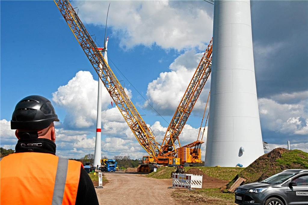 Ein Mann mit Warnweste schaut bei der Errichtung eines Windrades im Bürgerwindpark Hengeler-Wendfeld zu (Archivbild).