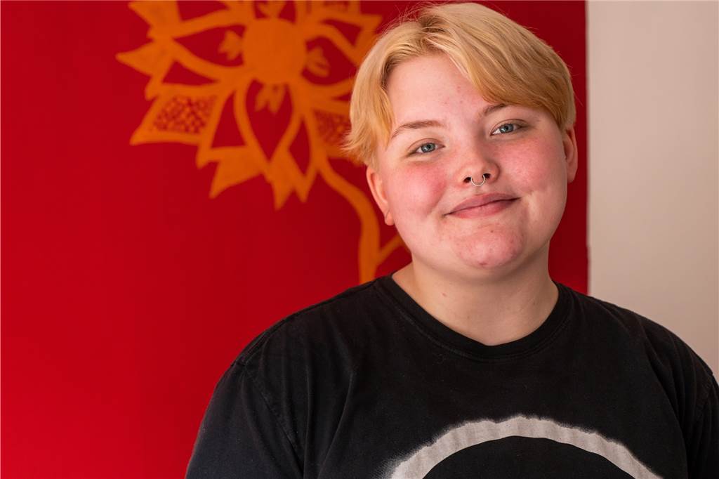 Als Mädchen geboren: Alex Terheyden fühlt sich gefangen im falschen Körper Alex Terheyden steht vor einer roten Wand.