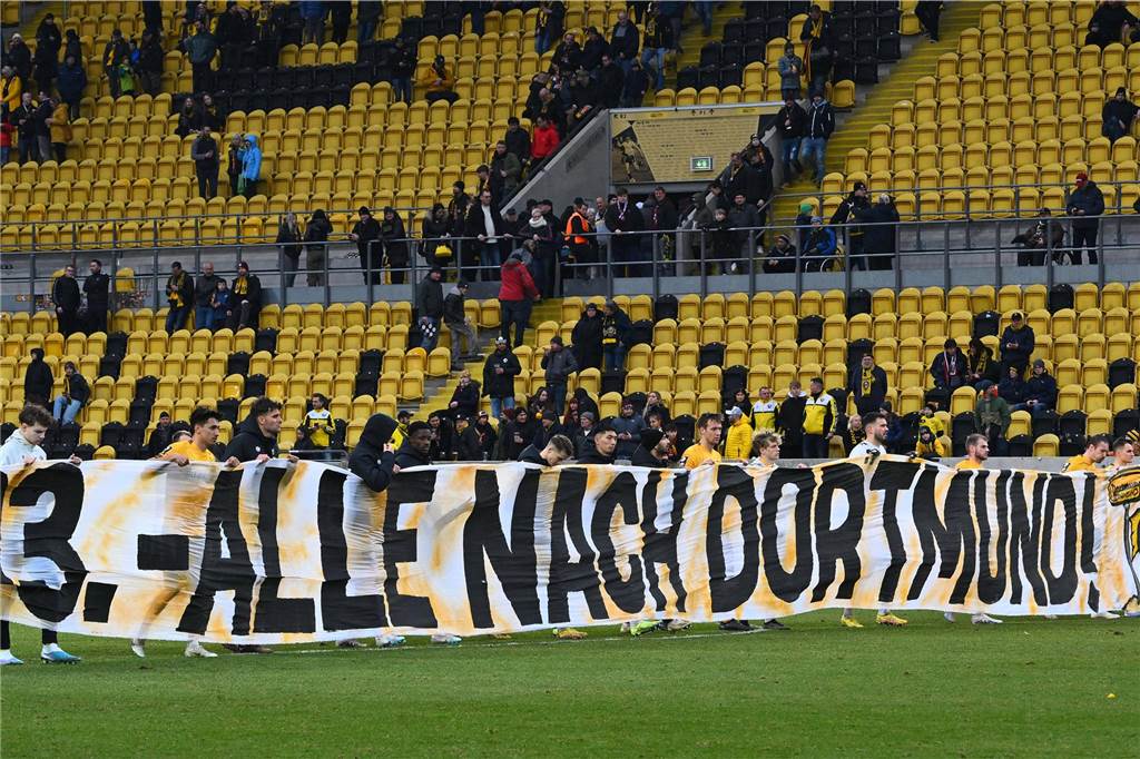 Dresden reist mit 7.000 Gäste-Fans zum BVB: Polizei wendet sich mit Brief an Dynamo-Anhänger Die Spieler von Dynamo Dresden halten ein Banner in die Höhe.