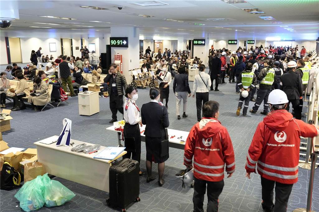 Mitarbeiter von Japan Airlines stehen auf dem Flughafen Haneda, nachdem ein Passagierflugzeug bei der Landung in Brand geraten war.