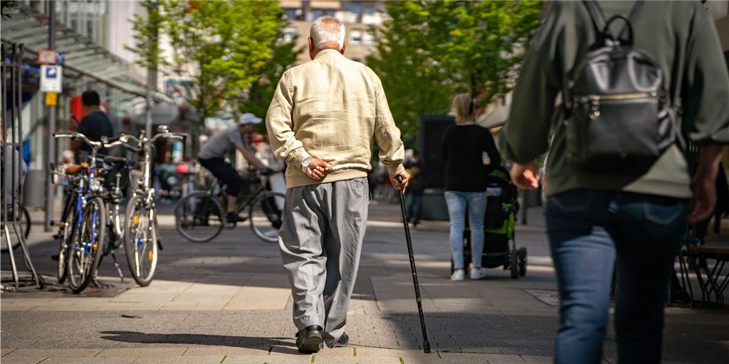 Was Sie über die Rentenerhöhung wissen sollten Ein älterer Herr spaziert mit einem Gehstock durch die Straße.