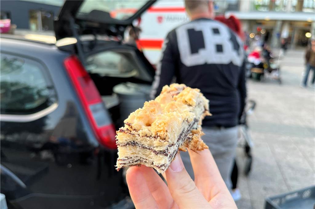 Sylwia Rother kocht für Bedürftige am Hauptbahnhof Ein Stick Mohnkuchen in einer Hand.