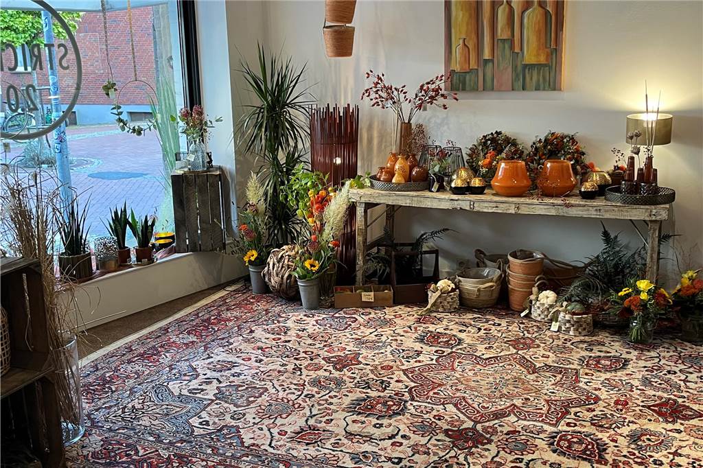 Pop-up-Store: Blumen Stricker schnuppert endlich Mittelstraßen-Luft Viele Pflanzen stehen auf einem Holztisch, auf dem Boden liegt ein Teppich.