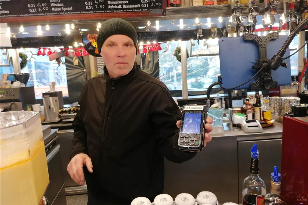 Glühwein-Stände haben unterschiedliche Regeln zur Kartenzahlung Ein Mitarbeiter des Glühweinstands Café Bar auf dem Weihnachtsmarkt Dortmund zeigt ein Kartenlesegerät.