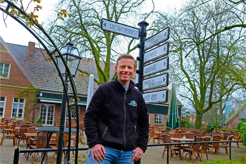 Brüggemanns hoffen auf Storchenbabys an der Haarmühle in Alstätte Guido Brüggemann vor einem Schild, das auf das Storchennest hinweist. Im Hintergrund der Landgasthof.