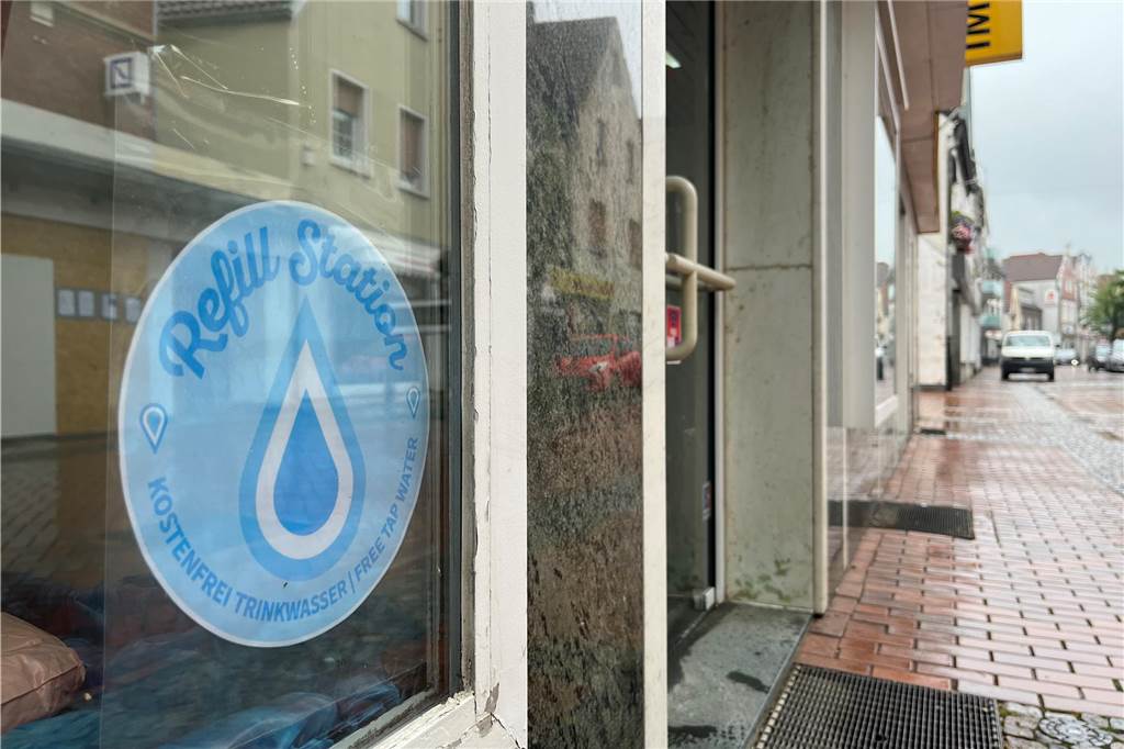 Trinkbrunnen und Auffüll-Station: „Coole“ Projekte zur Klimaanpassung An dem "Refill"-Logo, das hier im Schaufenster des Friseursalons "Haar Zwei Ooh" angebracht ist, sind die Geschäfte zu erkennen, die an der kostenlosen Trinkwasser-Aktion teilnehmen.