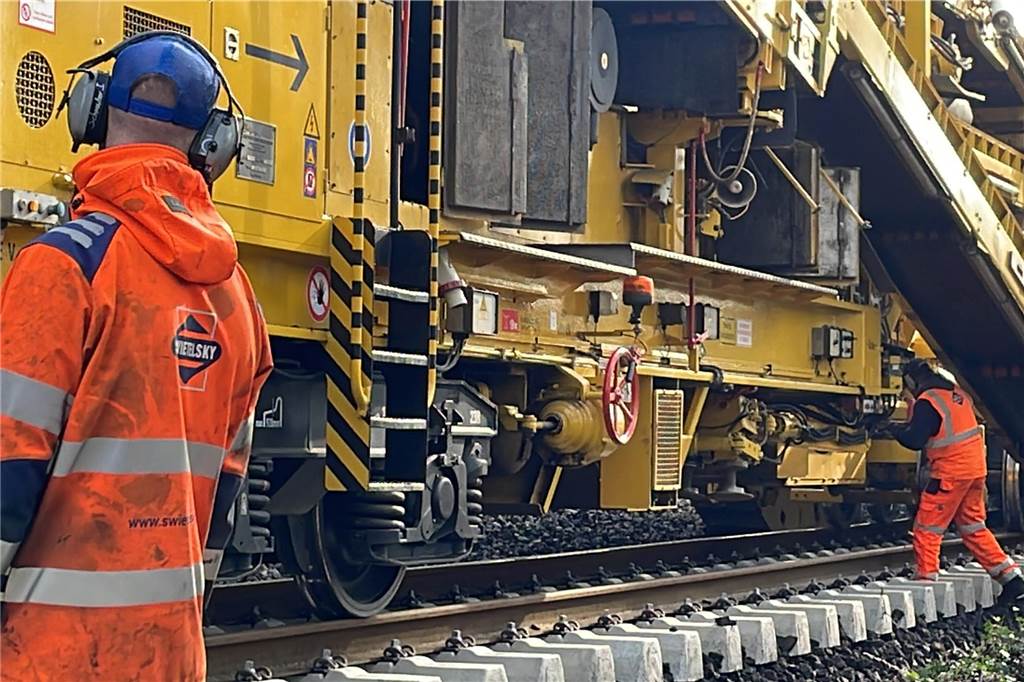 Mega-Maschine tauscht Bahnschwellen und reinigt Schotter im Sekundentakt An den Maschinen arbeiten gut 30 bis 40 Bauarbeiter. Sie überwachen den ganzen Prozess, fahren die Maschinen und Krane und legen zum Teil auch noch selbst Hand an.