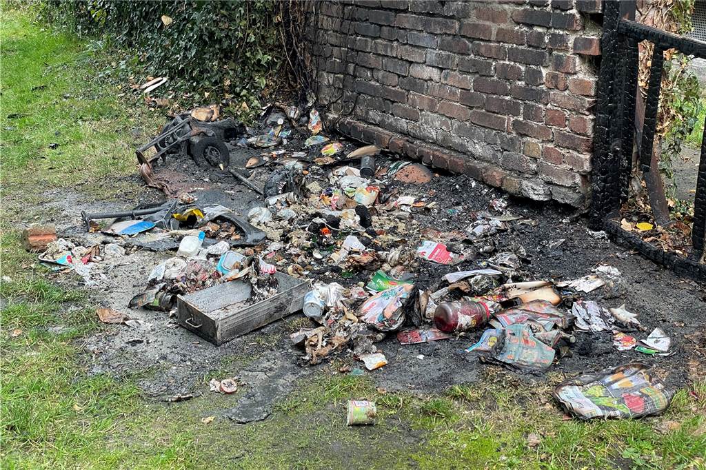 Vom Knistern der Flammen geweckt: So haben Anwohner die Mülltonnen-Brände erlebt Verkohlte Müllreste und Asche liegen auf dem Rasen an der Germanenstraße. Die Backsteinmauer ist rußgeschwärzt.