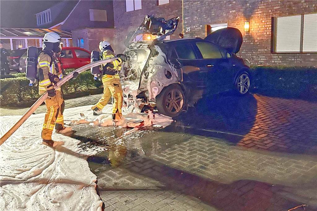 Feuerwehrleute löschen an der Kerssenbrockstraße in Vreden ein Auto, das in Brand geraten war.