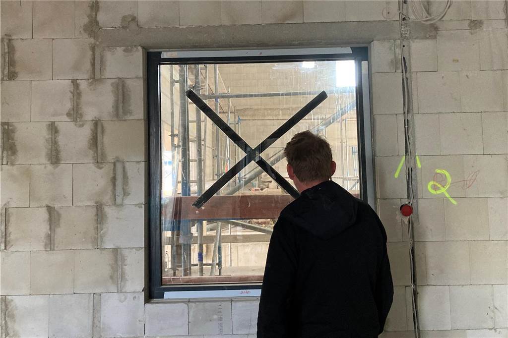 Bestatter Sascha Müller aus Waltrop schaut durch ein Fenster im Rohbau seines Tierkreamatoriums in eine Halle.