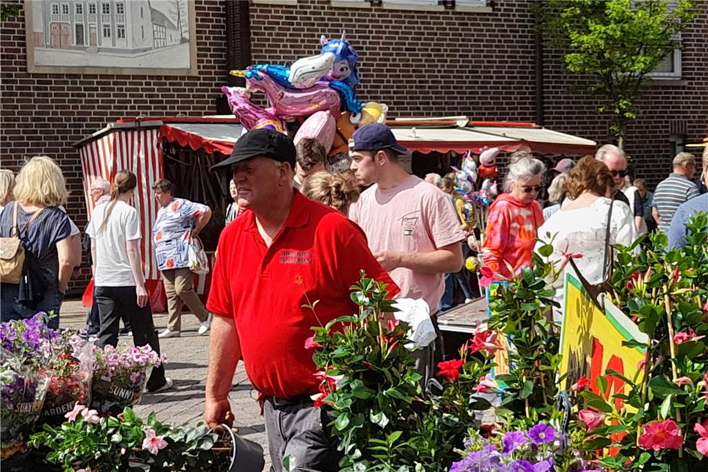 An einem Stand wurden verschiedene Blumen gekauft, die einer der Verkäufer lautstark bewarb.