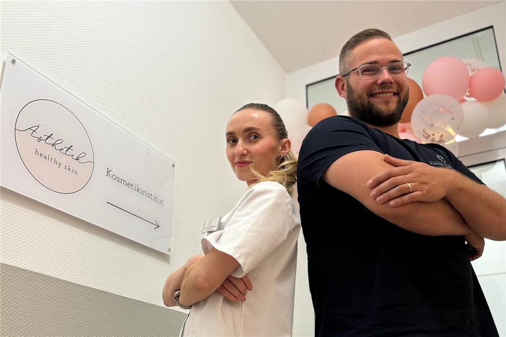 Ahauser Hautarztpraxis gründet Kosmetikstudio Anastasiya Dudarenka und Lars Kaminski stehen mit dem Rücken aneinander am Eingang des Studios