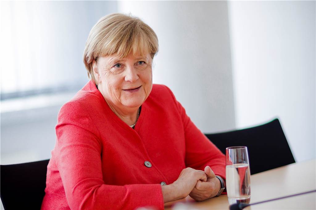 Angela Merkel im Interview: „Jetzt bin ich frei“ Angela Merkel sitzt vor einem Glas Wasser und lacht.
