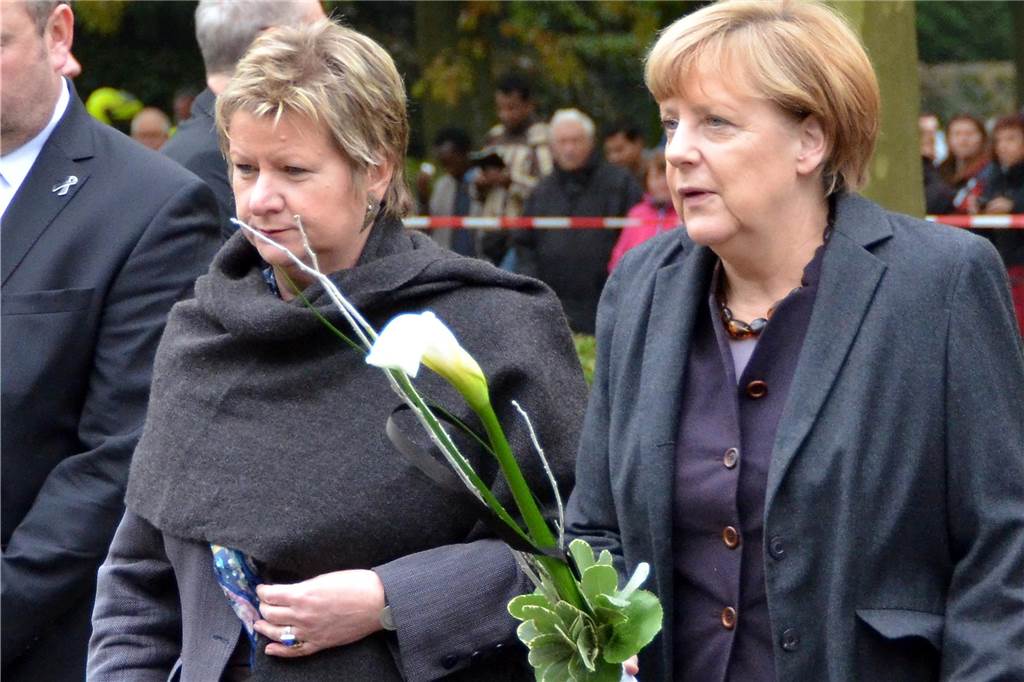 Sylvia Löhrmann zum 24. März 2015: „Eine menschliche Herausforderung“ Sylvia Löhrmann begleitet Angela Merkel zur Gedenkstätte in Haltern, in der Hand halten sie weiße Kalla.