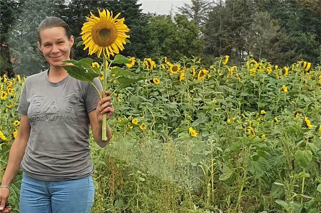 Angela Zanirati stirbt mit nur 44 Jahren: Fünf- und Achtjähriger verlieren ihre alleinerziehende Mutter Die Dortmunderin Angela Zanirati hält eine Sonnenblume in die Kamera. Hinter ihr sind weitere Sonnenblumen zu sehen.
