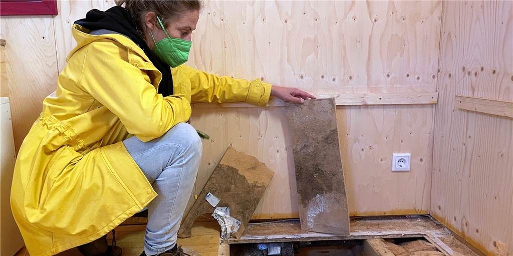 „Unhaltbare Zustände“ - Schimmel in der Naturkita nicht einmal zwei Jahre nach dem Bau Anika Pirronello vom Naturkindergarten Glückspilze Haltern am See e.V. zeigt den Schwarzschimmel unter den Bodendielen.