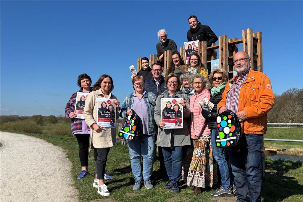 Dorstener Kulturrucksack feiert zehnten Geburtstag: 30 Angebote Anke Klapsing-Reich und die anwesenden lokalen Partner halten Plakate in der Hand und stehen an der Lippe Lese Lounge in Dorsten.