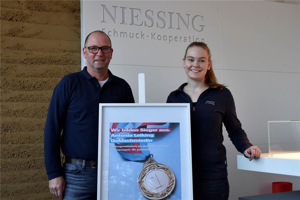Antonia Leiking (21): Von der Praktikantin zur Goldschmiedin mit Auszeichnung Antonia Leiking (r.) zusammen mit ihrem Ausbildungsleiter (l.), präsentieren stolz die Urkunde der Handwerkskammer.