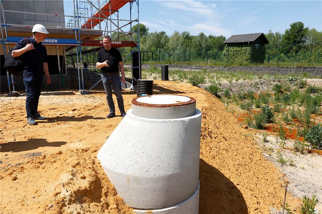 Heizen mit Eis? Neue Erfindung macht die zweite Miete überflüssig Architekt Martin Kolander bei der Besprechung mit seinem Kollegen Michael Heimsath. In der Mulde (rechts) soll der Eisspeicher versenkt werden. Das Schachtbauwerk mit dem Gullydeckel zeigt an, wie hoch noch aufgeschüttet werden muss.