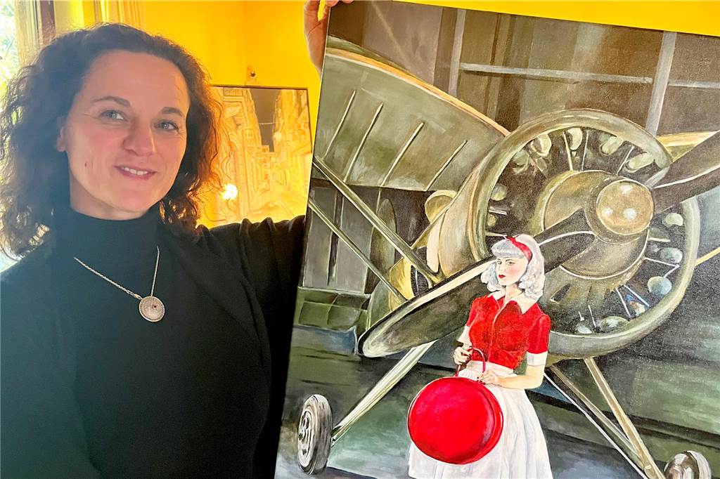 Art-ig: Zwei Frauen wollen Künstler um Ahaus verbinden Arianna Mora hält ein selbstgemaltes Bild von einer Frau vor einem Flugzeug in Händen.