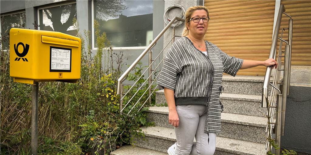 „Karins Nähstube“: Arzu Saglam Kurtcus Familie übernimmt Ladenlokal Eine Frau steht neben einem gelben Briefkasten auf den Treppenstufen eines Ladeneingangs.