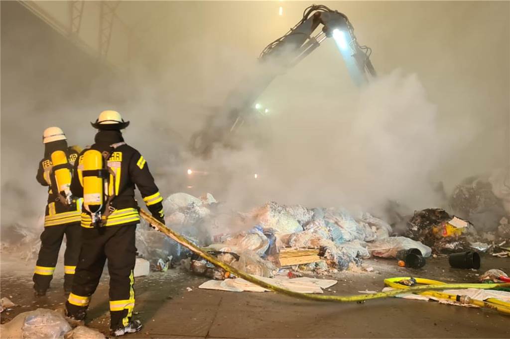 Feuerwehrleute löschen einen Brand in einer Halle.