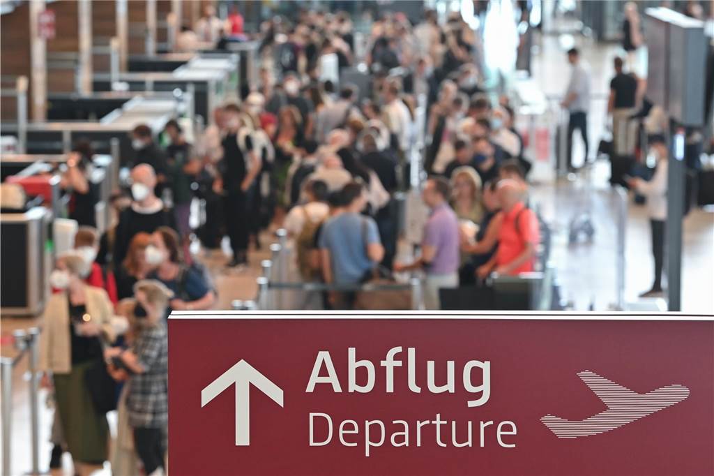 Ferienende in sieben Bundesländern: ADAC erwartet viel Verkehr zum Wochenende Reisende warten an einem Check-in für ihren Abflug.