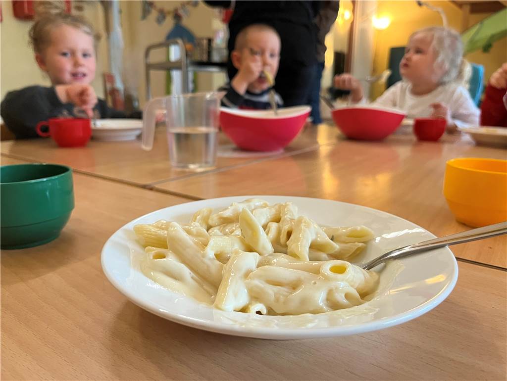 Alleskönner: Was Erzieher im Lummerland jeden Tag für Kinder leisten Ein Teller Käsenudeln in der Kita Lummerland in Ickern im Hintergrund sieht man essende Kinder.