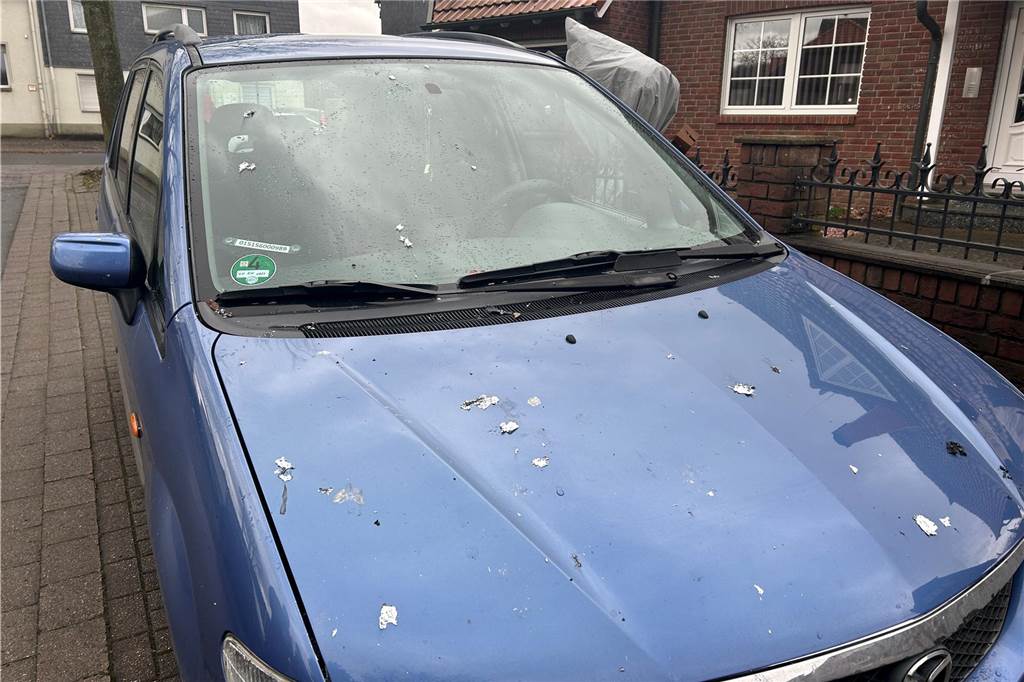 Blaues Auto mit Lackschäden und Ruß auf der Motorhaube