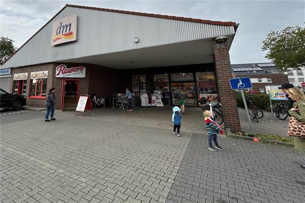 Menschen stehen auf dem Parkplatz vor der DM-Filiale in Vreden.