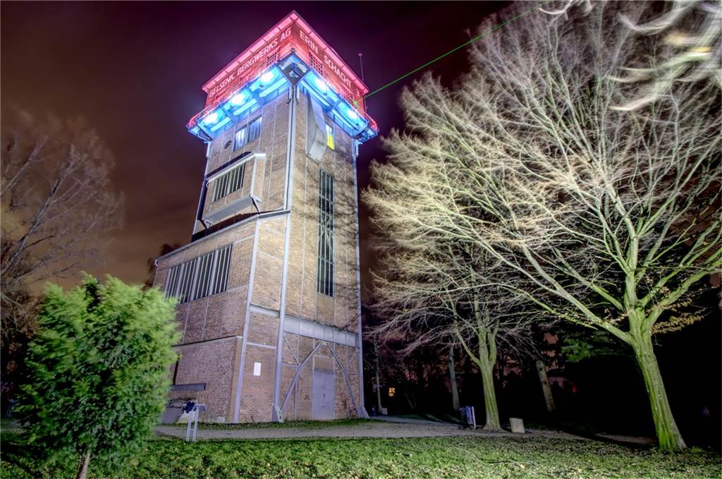 Zu sehen ist der angeleuchtete Turm der Zeche Erin, von dem ein grüner Laser abstrahlt.