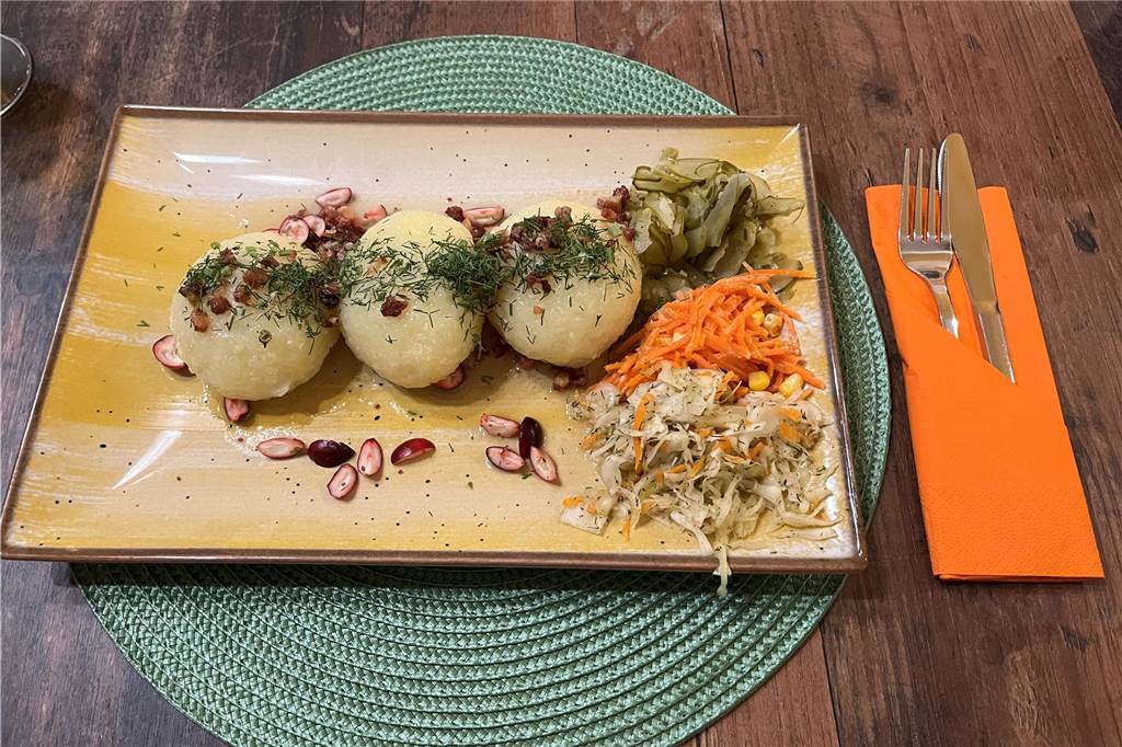Restaurant „Von Herzen“ im Check: Traditionelle polnische Küche wie bei Mama Ein Teller mit drei Kartoffelklößen mit Fleischfüllung sowie kalten Beilagensalaten und Salzgurken.