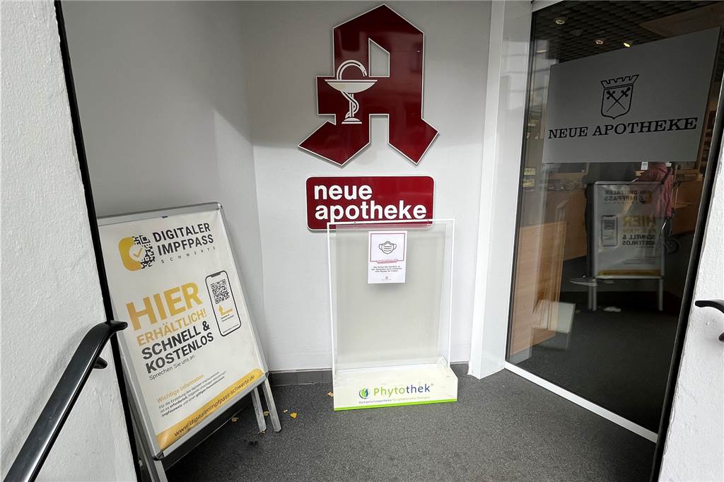 Neuer Corona-Impfstoff: Frisch geimpft, aber noch kein digitaler Nachweis Neue Apotheke Schwerte mit dem Schild "Digitaler Impfpass" am Eingang