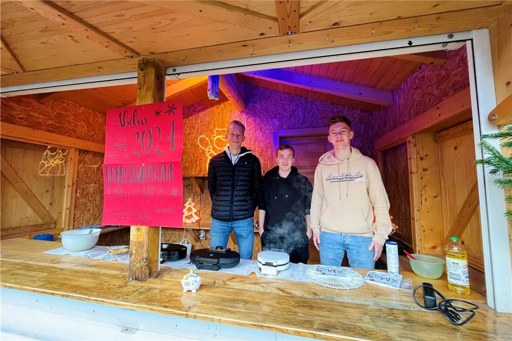 Drei Schüler des Halterner Gymnasiums backen in einem Holzstand Waffeln. 