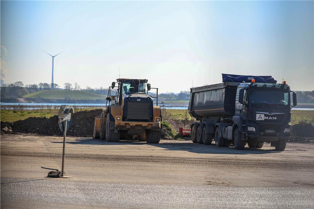 Ein Radlader und ein Lkw stehen auf einer Freifläche.