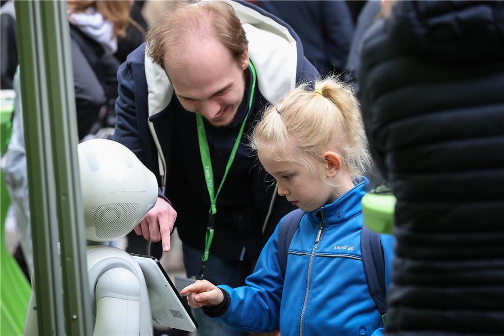 Ein Mädchen interagiert mit einem Roboter.