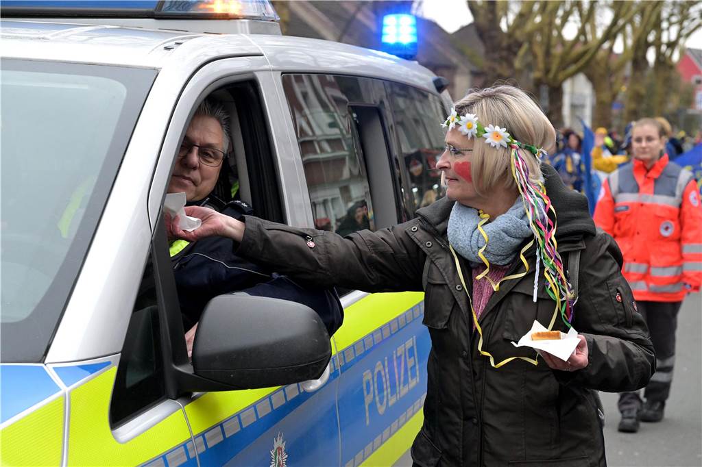 Lünen-Süd feiert einen bunten Karnevalsumzug Eine Frau gibt einem Polizisten etwas.
