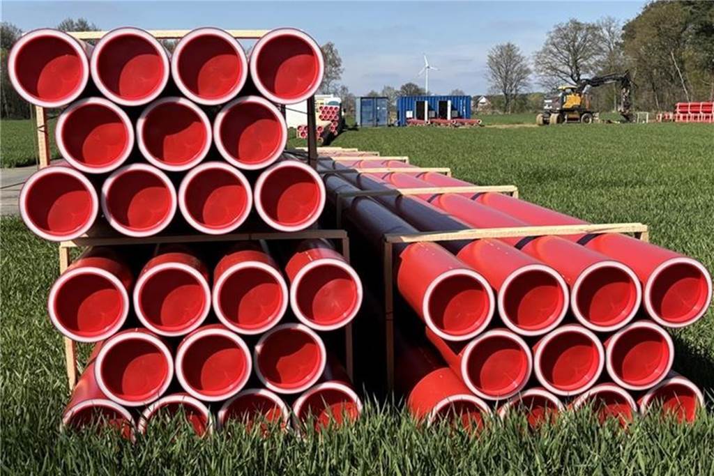 Superstromtrasse A-Nord: Baustart an der Vennstraße in Südlohn Rote Rohre liegen auf einem Feld an der Straße K21 in der Gemeinde Südlohn. Im Hintergrund sieht man Baufahrzeuge. Hier wird an der Stromtrasse Nord-A gebaut.