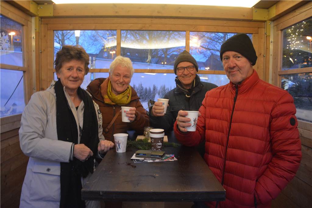Eine Gruppe steht in einer Weihnachtshüte und trinkt Glühwein dabei. 