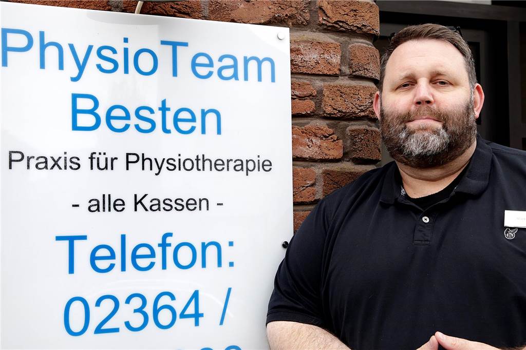 Lange Wartezeiten für Physiotherapie: „Haben einen Personalnotstand“ Physiotherapeut Mark Besten steht neben seinem Praxisschild.