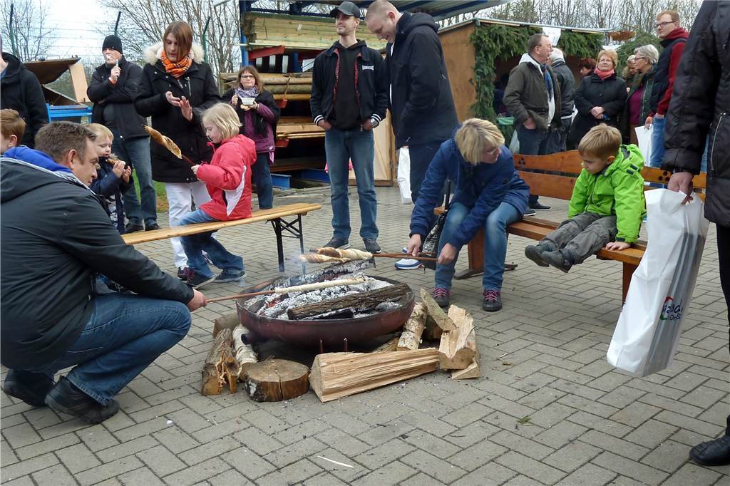Kunsthandwerk im Meisenhof: Weihnachtsmarkt öffnet wieder im Gefängnis Kinder und Eltern backen Stockbrot.