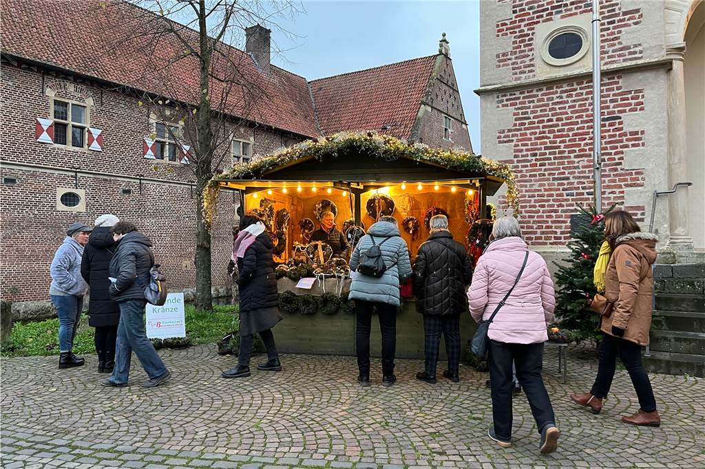 Menschen stehen vor einem Stand, der Weihnachtskränze verkauft.