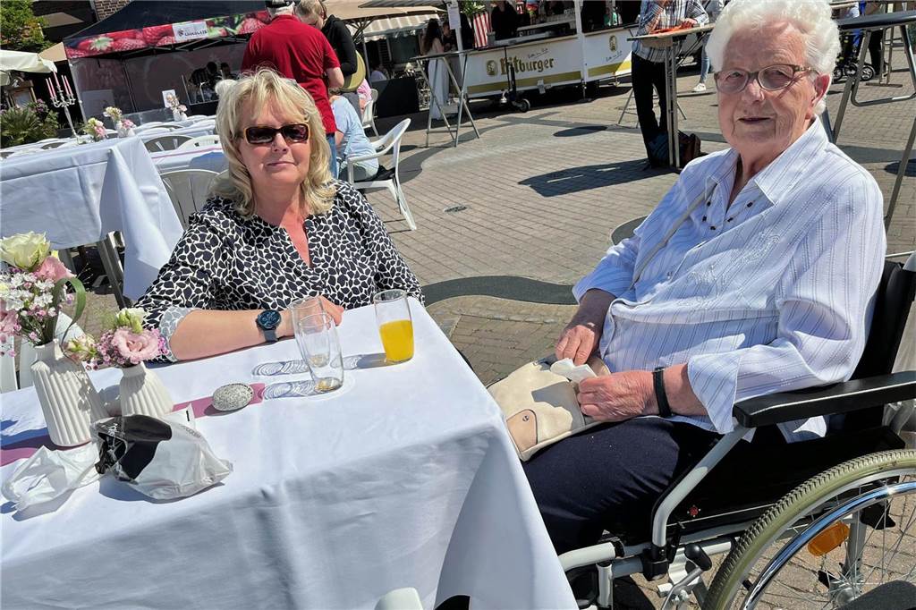 Sonne lockte früh zum Olfener Frühling 2024: Besucher in Kauf-Laune Menschen sitzen an einer Tafel auf dem Marktplatz in Olfen
