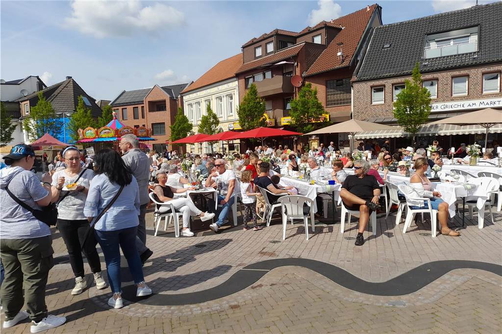 Auf dem Marktplatz waren Tische und Bänke aufgestellt, wo sich viele Besucher niederließen und aßen und tranken.