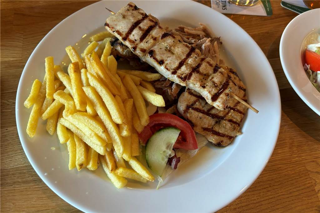 Pommes und Fleisch liegen auf einem Teller auf einem Tisch.