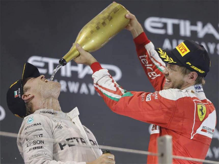 Rosberg feiert WM-Triumph im Zitter-Finale Auf dem Podium bekommt Rosberg auch Partyhilfe von Landsmann Sebastian Vettel. Foto: Valdrin Xhemaj