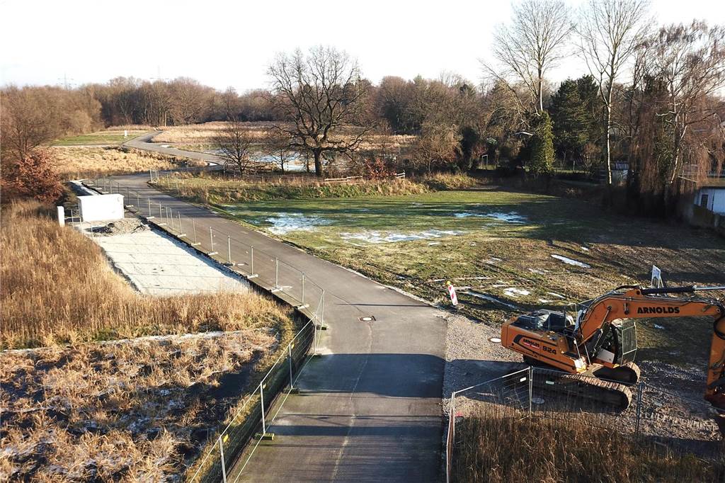 Noch ein Bagger im Baugebiet Am Emscherufer: Winterruhe an der Emscher Auf dem von der Wartburgstraße aus betrachtet vorderen Teil des Geländes "Am Emscherufer" steht ein Bagger. Dahinter ist die bekannte "Alte Eiche" zu sehen, die das Gebiet noch grüner macht. Im hinteren Teil ist der Friedhof zu sehen. Die Emscher verläuft hier am linken Bildschirmrand. Rechts ist die Bebauung entlang der Heerstraße.
