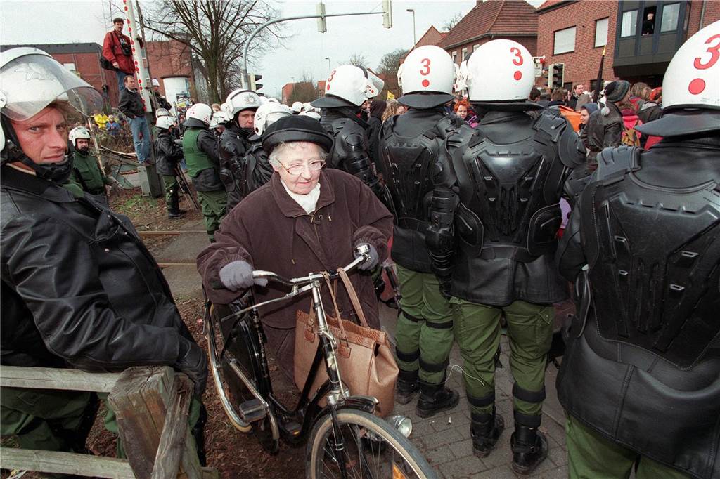 Auf dem Weg zum Einkaufen schiebt diese Einwohnerin von Ahaus am Freitag (20.3.98) ihr Fahrrad durch eine dichte Polizeikette in der Innenstadt. Mehrere Tausend Atomkraftgegner protestierten gegen die für den Nachmittag erwartetet Ankunft des Castor-Transports im Zwischenlager. dpa COLORplus +++ dpa-Bildfunk +++