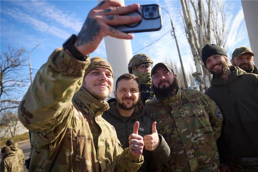 Ein Jahr Krieg in der Ukraine: Diese Orte und Geschehnisse sind besonders in Erinnerung geblieben Auf diesem vom Pressebüro des ukrainischen Präsidenten zur Verfügung gestellten Foto machen ukrainische Soldaten ein Selfie mit Wolodymyr Selenskyj (2.v.l), Präsident der Ukraine, während seines Besuchs in Cherson.